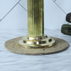 Close-up of the sturdy, polished brass base of the Ashoka Pillar statue, showing its fluted column design.
