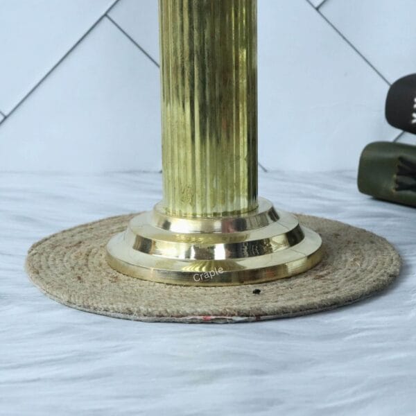 Close-up of the sturdy, polished brass base of the Ashoka Pillar statue, showing its fluted column design.