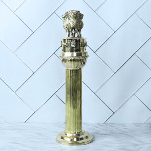 Full-length studio photograph of the tall brass Ashoka Pillar against a neutral background.