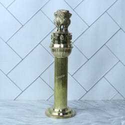 An angled, full-length view of the polished brass Ashoka Stambh sculpture.