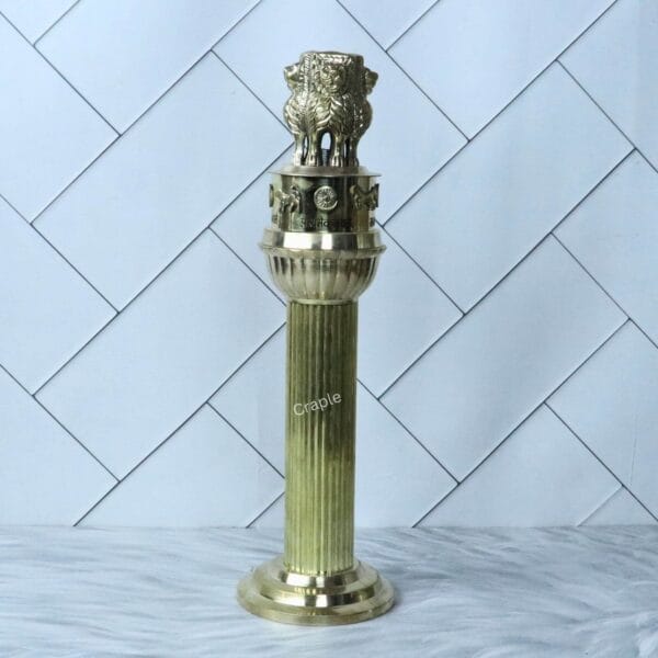 An angled, full-length view of the polished brass Ashoka Stambh sculpture.