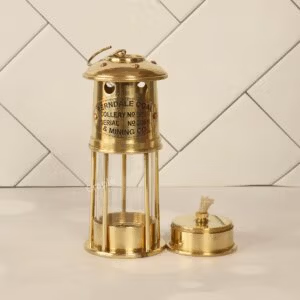 Handcrafted antique brass miner's lantern with a shiny finish, shown with its removable oil burner base.