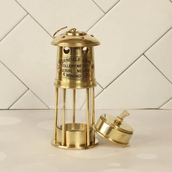 Handcrafted Antique Brass Miner’s Lantern-3 Angled view of the shiny brass miner's lamp with its oil burner base placed beside it at a tilt.