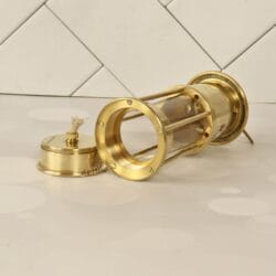 The brass miner's lantern lying on its side with the oil lamp base removed, showing the protective cage.