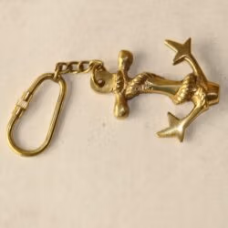 Handmade brass anchor keychain with rope detail, lying on its side to show the full length including the chain and carabiner clip.