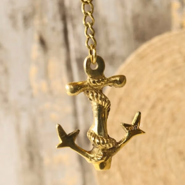 Detailed close-up of the handmade brass anchor charm hanging, showcasing the intricate rope wrapped around the shank.