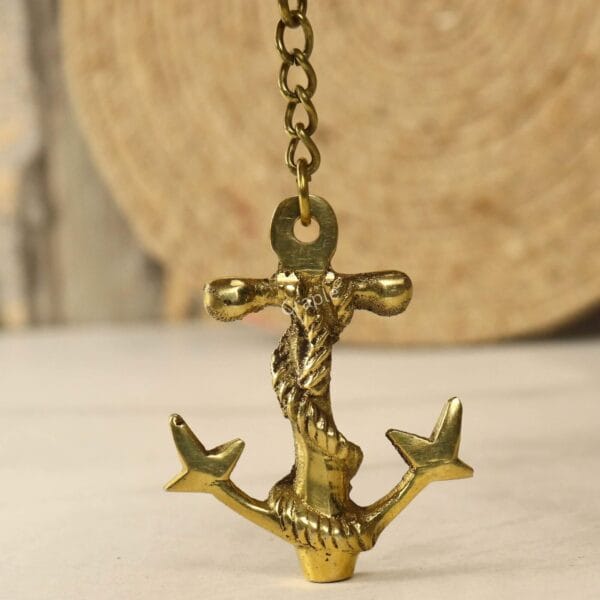 Handmade Anchor Rope Keychain-3 Front view of the nautical brass anchor keychain hanging from its chain against a rustic background.