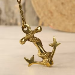 A dynamic angled view of the handmade brass anchor keychain, highlighting its shiny finish and three-dimensional rope detail.