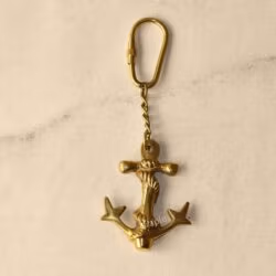 A flat lay of the entire brass anchor keychain, showing the anchor charm, link chain, and secure carabiner clip.
