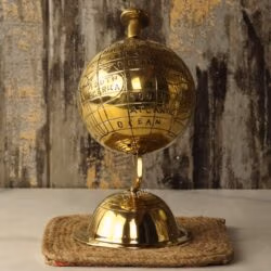 The spinning brass globe tilted to show the engraved continents of the world map on its polished surface.