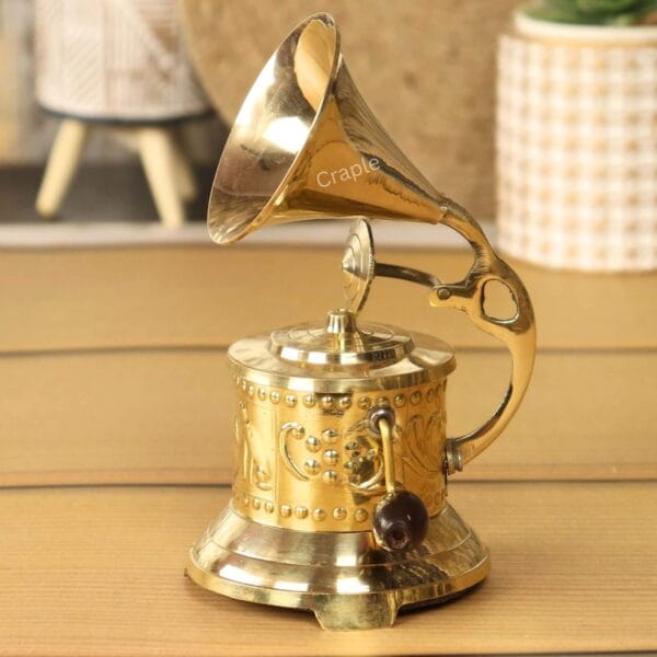 Side profile of a vintage-style brass gramophone showcasing the intricate embossed floral patterns on its base.