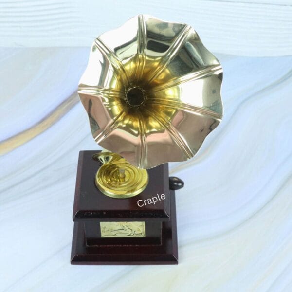 Top-down view looking directly into the shiny brass horn of the decorative miniature gramophone.