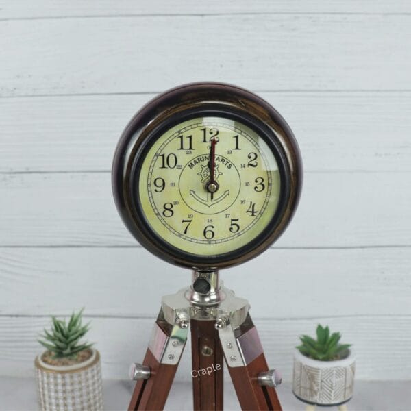 Close-up of the antique-style analog face on the wooden tripod desk clock, showing the numerals and hands.