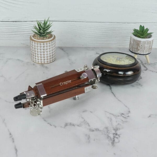 The surveyor-style clock with its wooden tripod legs collapsed and lying next to the clock head.