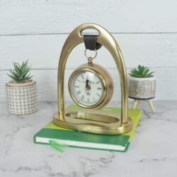 Angled view of the golden hanging desk clock resting on a book, displayed as a stylish office accessory.