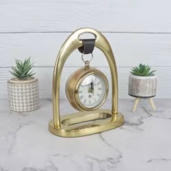 Front view of the golden tabletop clock with a hanging design, showing the elegant arch and stable base.