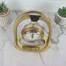 Top-down view of the hanging desk clock, highlighting the leather strap suspension and the shape of the golden aluminum frame.