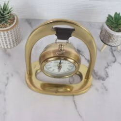 Top-down view of the hanging desk clock, highlighting the leather strap suspension and the shape of the golden aluminum frame.