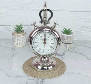 Front view of a vintage stopwatch-style hanging desk clock with a nickel finish, Roman numerals, and a sturdy base.