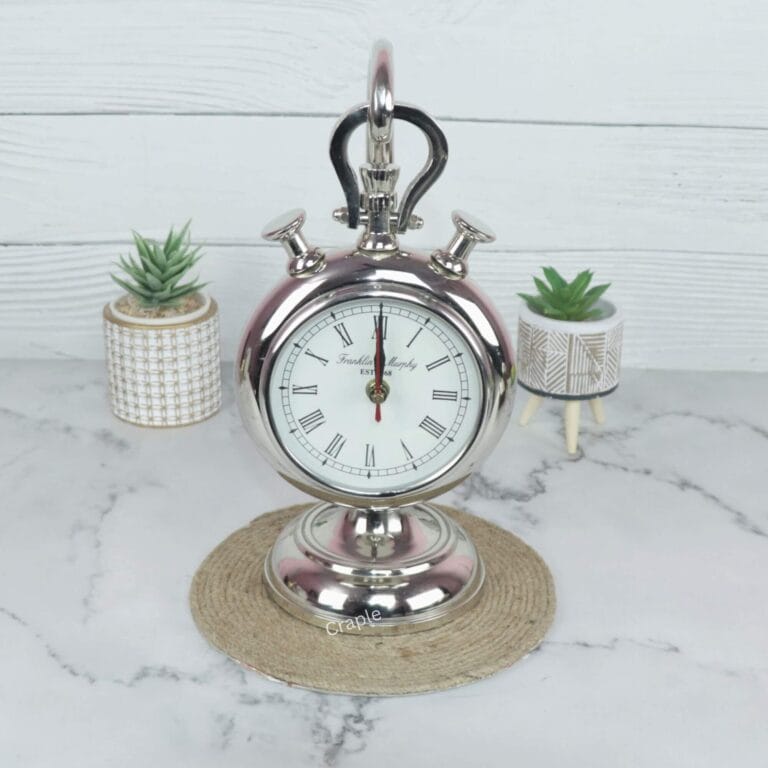 Front view of a vintage stopwatch-style hanging desk clock with a nickel finish, Roman numerals, and a sturdy base.