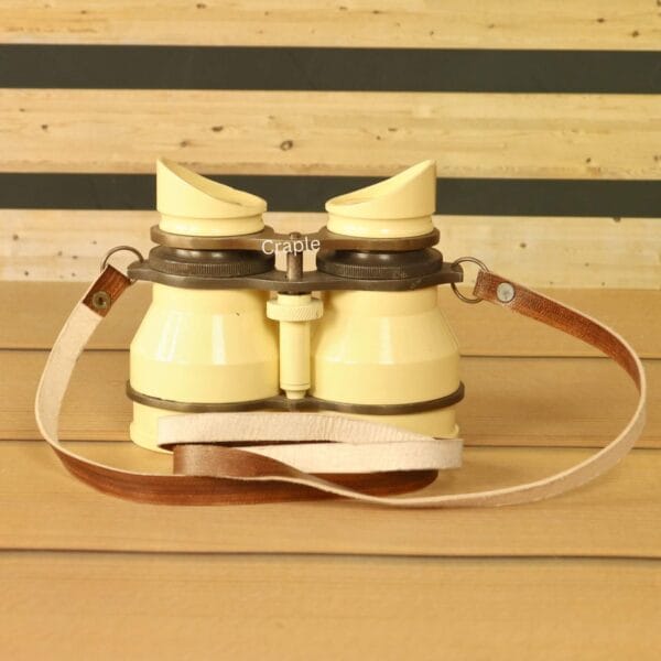 Angled view of vintage-style light yellow aluminum binoculars with leather strap – adjustable focus retro binoculars.