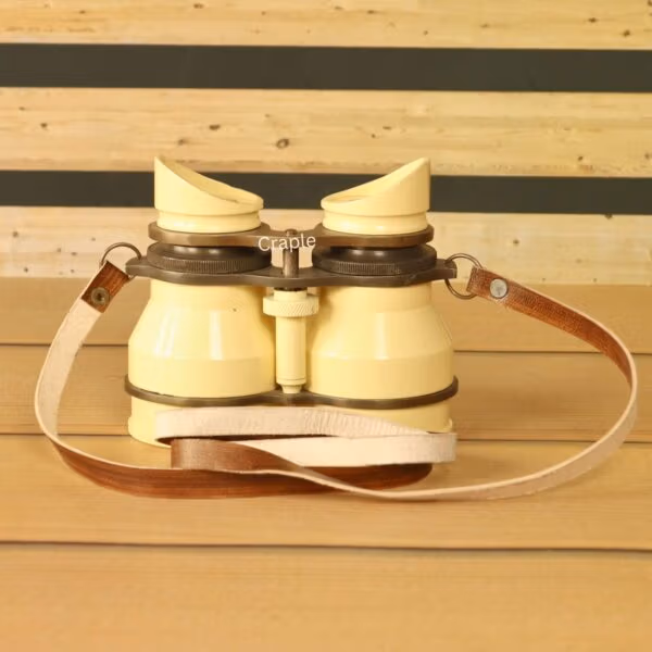 Angled view of vintage-style light yellow aluminum binoculars with leather strap – adjustable focus retro binoculars.