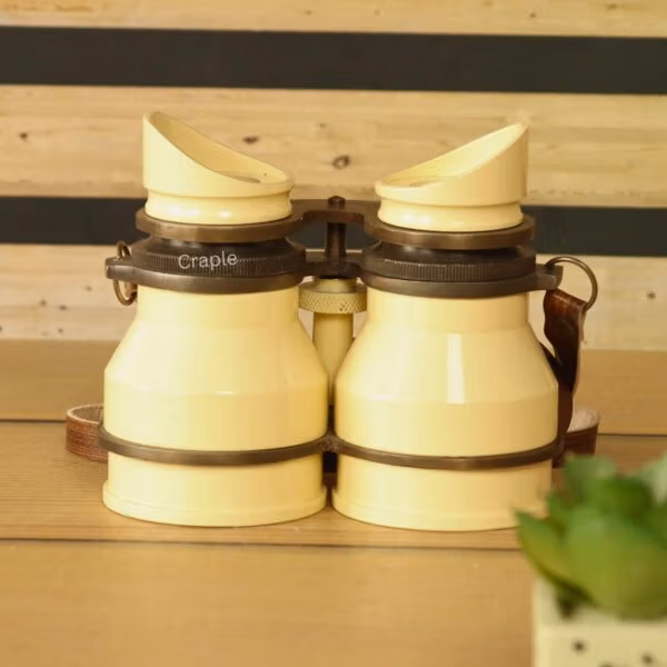 Stacked retro light yellow aluminum binoculars with leather straps – collectible decorative binoculars or unique gift idea.
