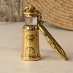 Solid brass lighthouse keychain with a shiny finish and a secure carabiner clip, standing upright.