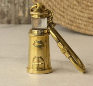 Solid brass lighthouse keychain with a shiny finish and a secure carabiner clip, standing upright.