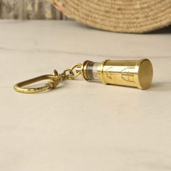 Close-up view of the brass lighthouse keychain on its side, focusing on the strong carabiner clip.