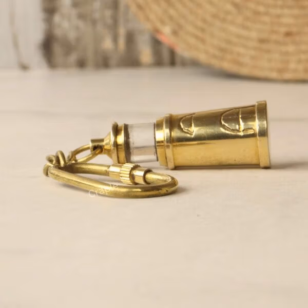 Angled view showing the connection point between the brass lighthouse charm and the keychain.