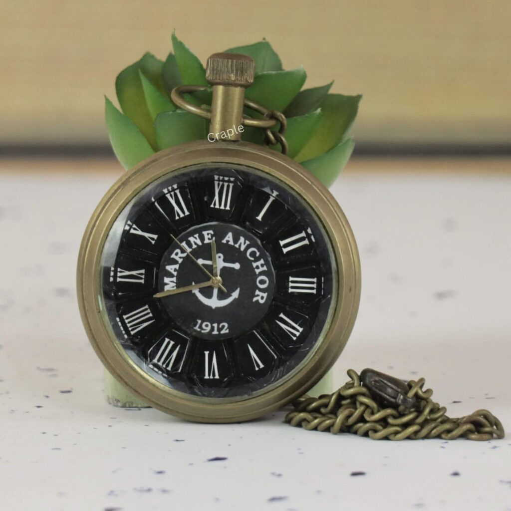 Antique brass 'Marine Anchor 1912' pocket watch with a black nautical dial, Roman numerals, and a matching chain.