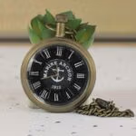 Antique brass 'Marine Anchor 1912' pocket watch with a black nautical dial, Roman numerals, and a matching chain.