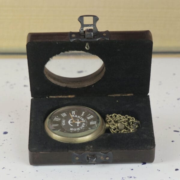 The antique brass pocket watch and chain presented inside its open, felt-lined wooden gift box.