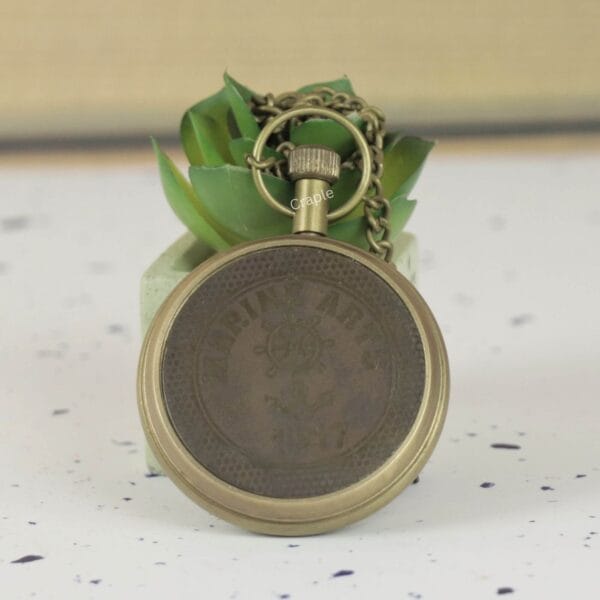 The reverse side of the antique brass pocket watch, showing the detailed casing and attached chain.