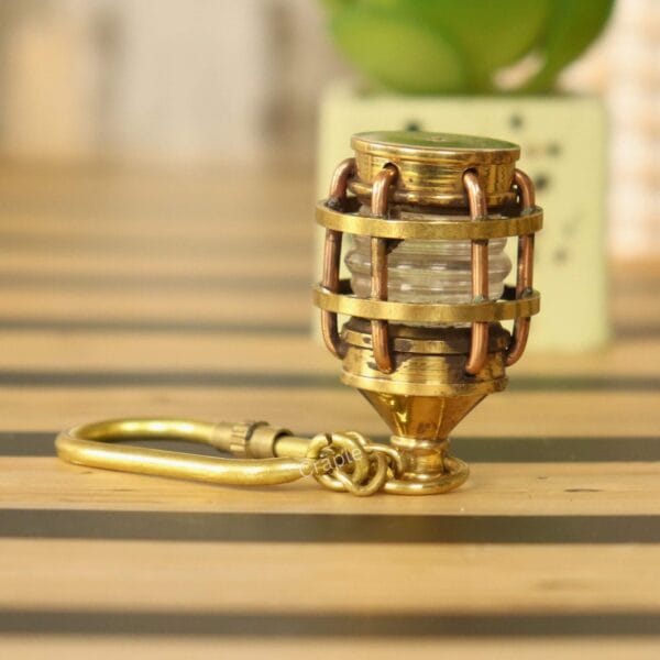 Angled side view of the brass lantern keychain showing the secure carabiner clip and protective cage detail.