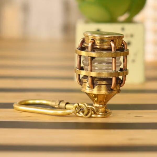 Angled side view of the brass lantern keychain showing the secure carabiner clip and protective cage detail.