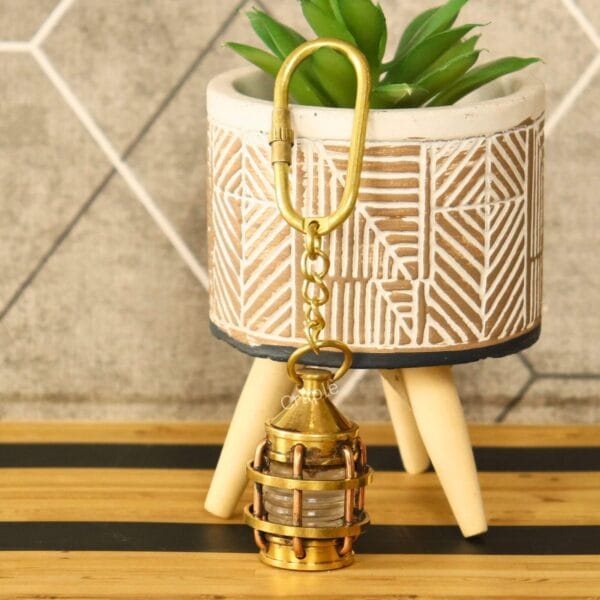 The miniature lantern keychain hanging from a decorative pot, showcasing its use as a stylish accessory.