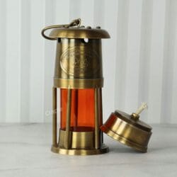 Antique brass nautical lantern with its functional oil lamp base removed to show the cotton wick.