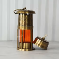 Three-quarter view of the brass ship's lantern with the oil burner component placed beside it.