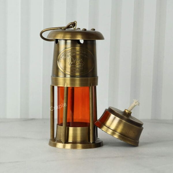 Orange Glow Nautical Lantern-3 Three-quarter view of the brass ship's lantern with the oil burner component placed beside it.