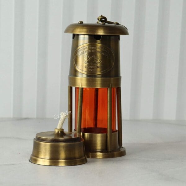 Orange Glow Nautical Lantern-5 Low-angle shot of the tabletop brass lantern showing the removable wick and oil reservoir.
