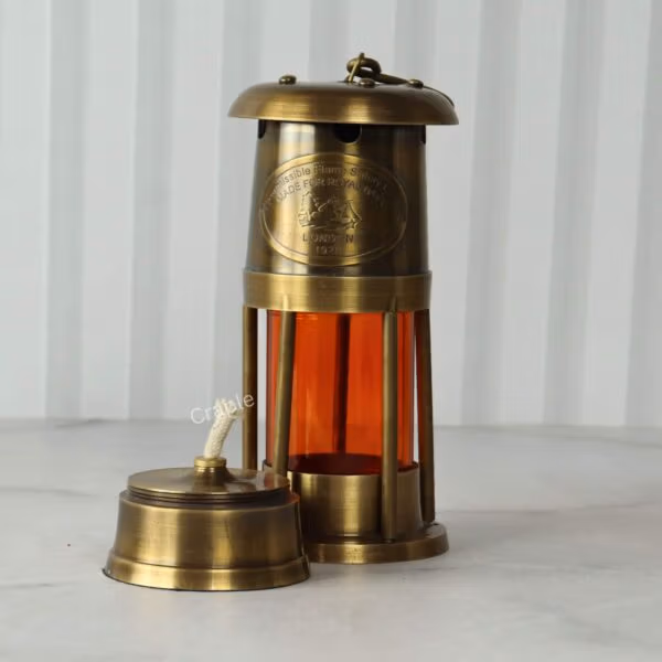 Low-angle shot of the tabletop brass lantern showing the removable wick and oil reservoir.