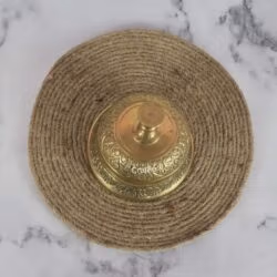 Top-down view of the vintage brass service bell, focusing on the push-button plunger and the engraved dome top.