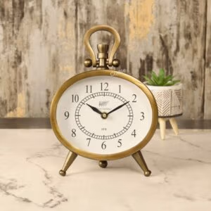 Antique oval desk clock with an antique brass finish, featuring a white face and black numerals, standing on a marble tabletop.