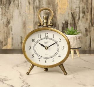 Antique oval desk clock with an antique brass finish, featuring a white face and black numerals, standing on a marble tabletop.