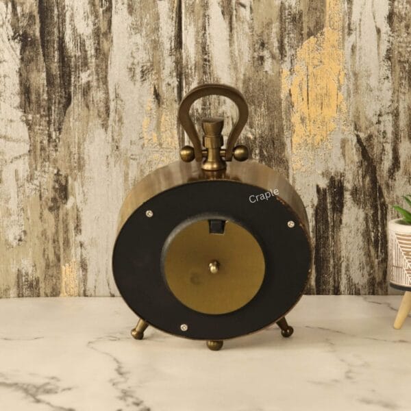 Back view of the antique oval desk clock, showing the black casing and the battery compartment.