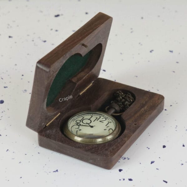 The artistic numeral pocket watch nestled inside its open, dark wood presentation box with green felt lining.