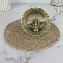 Underside of the brass desk bell, revealing the internal metal clapper and ringing mechanism.