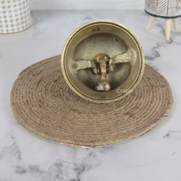 Underside of the brass desk bell, revealing the internal metal clapper and ringing mechanism.
